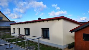 A modern house with a red roof, a small front yard, and a metal railing. - Holiday Home 'Waldblick' with Private Terrace, Private Garden and Wi-Fi (Reinharz)
