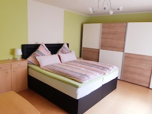 A bed with a black frame, a bedside table with a lamp, and a wardrobe with a mirror.