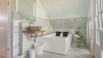 Ein modernes Badezimmer mit einer freistehenden Badewanne, einem großen Spiegel und einem Holzbodenregal.