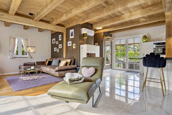 Un salon spacieux avec un fauteuil en cuir vert, un canapé marron et une table basse.