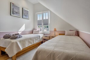 Ein Schlafzimmer mit zwei Betten, einem Fenster und einem Nachttisch.