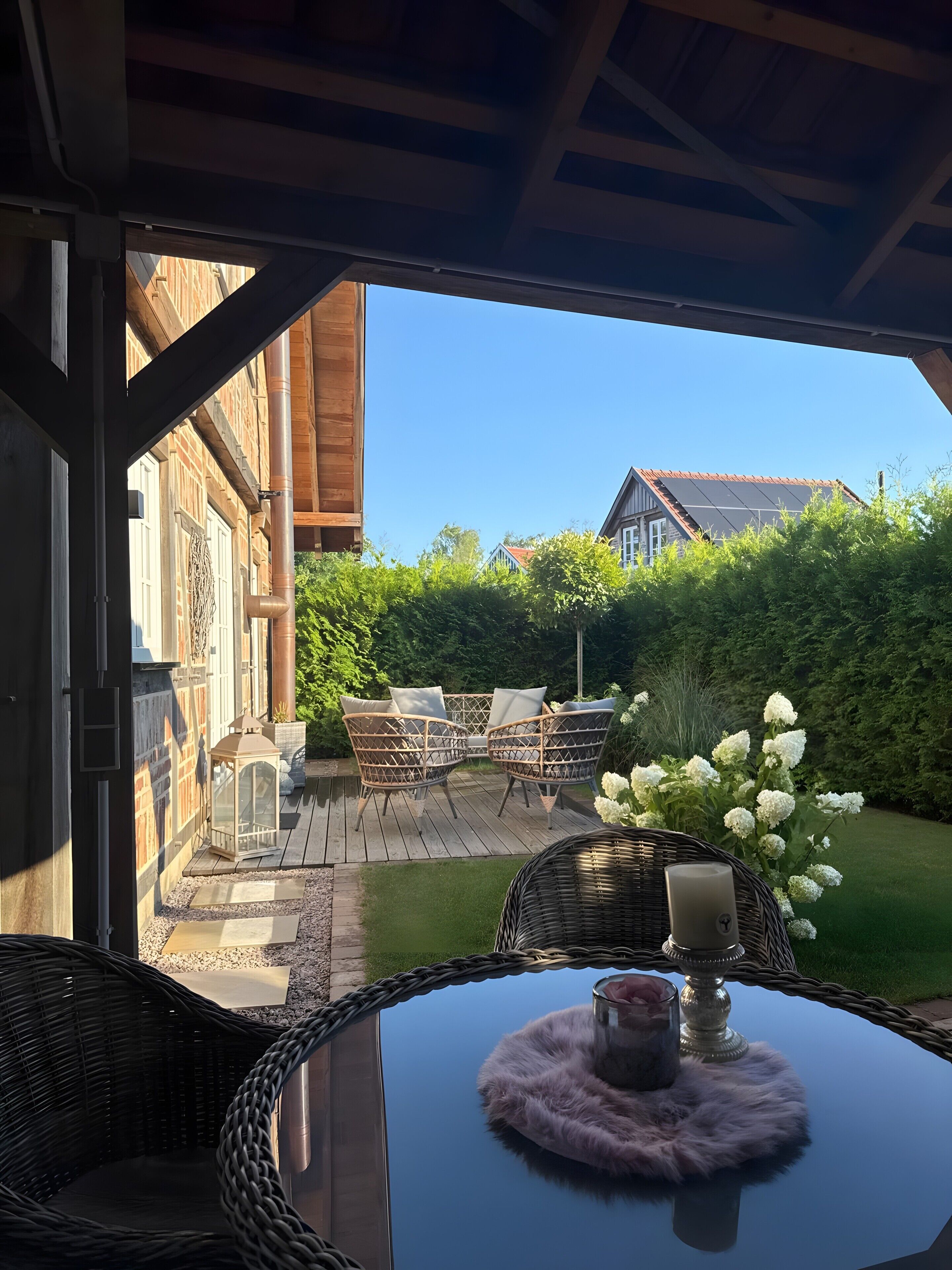 Eine Terrasse im Freien mit Korbmöbeln und einem Tisch mit Kerze.
