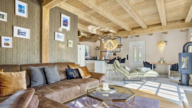 Ein modernes Wohnzimmer mit einem braunen Ledersofa, einem Glastisch und einer Holzzieldecke.