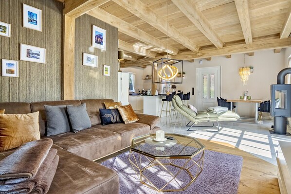 A modern living room with a brown leather sofa, a glass coffee table, and a wooden ceiling.