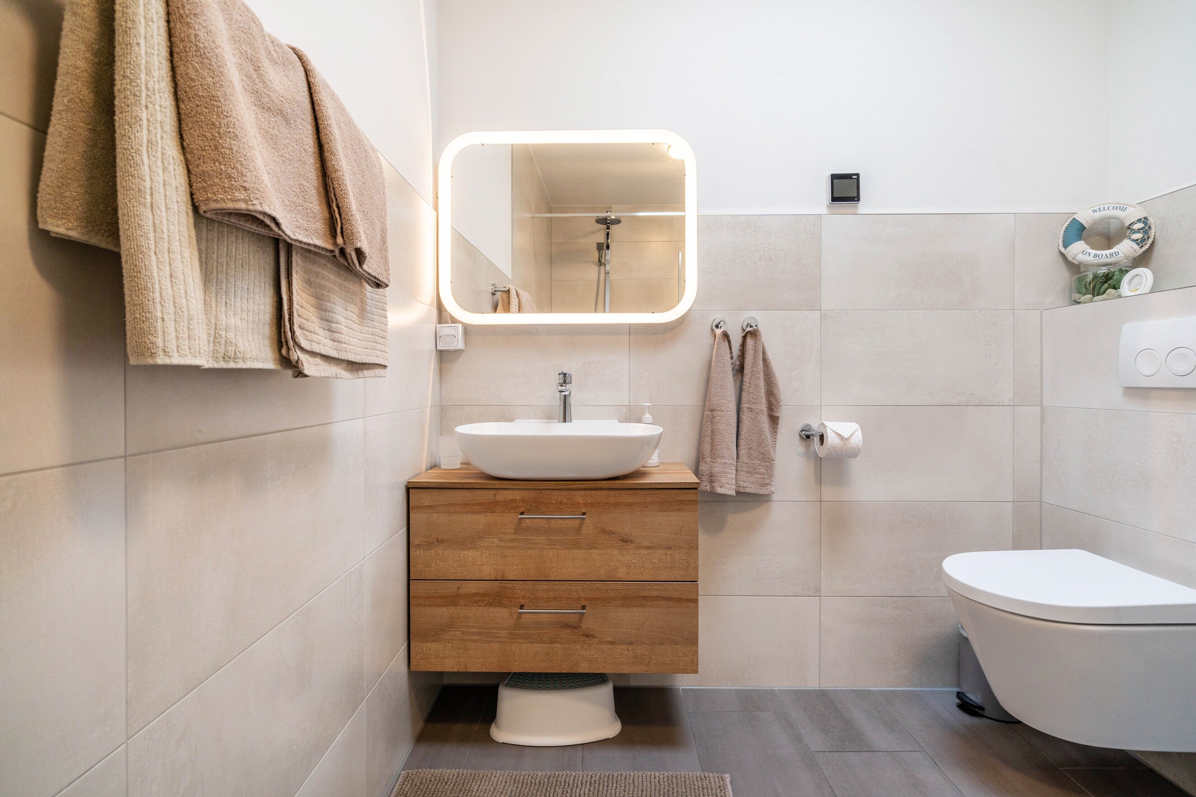 A modern bathroom with a white sink, wooden vanity, and a white toilet.