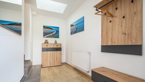 A modern interior with a staircase, wooden cabinets, a radiator, and wall-mounted artwork.