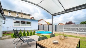 A covered patio with a pool, a wooden table, and outdoor seating.