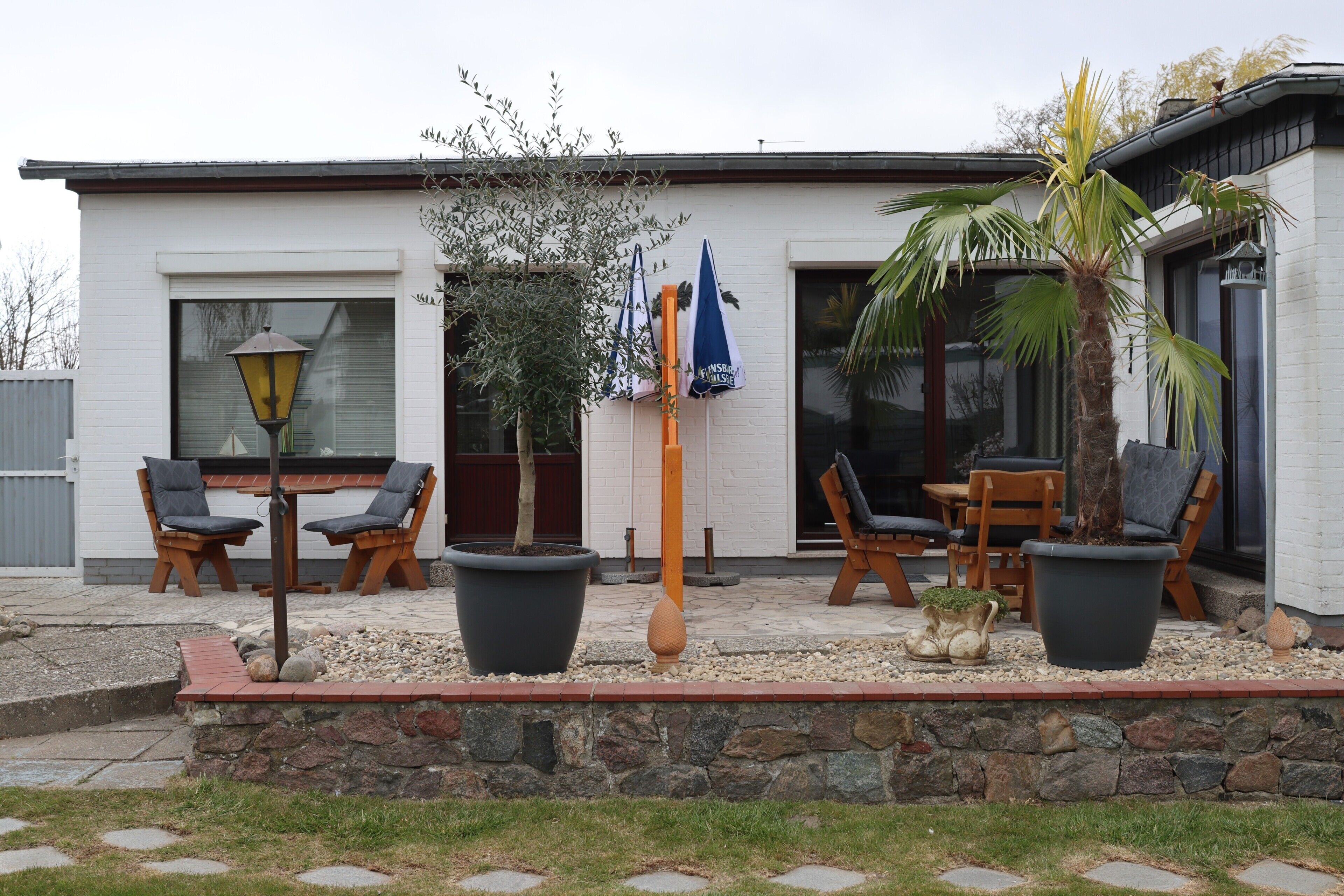 A modern house with a patio, outdoor furniture, and potted plants.