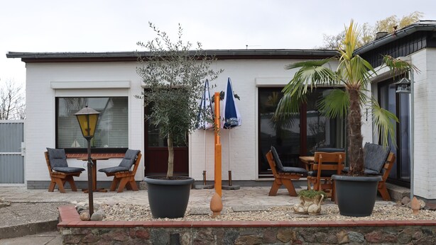 Una casa moderna con patio, mobili da esterno e piante in vaso.