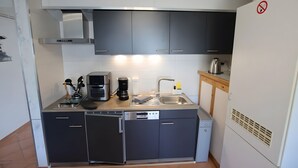 Una cucina compatta con mobili grigi, un forno a microonde integrato, una macchina da caffè e un lavello.