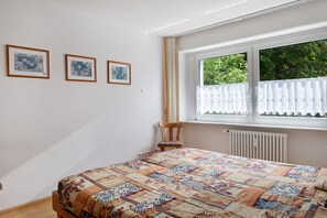 A bedroom with a bed, a window with curtains, and three framed pictures on the wall. - Apartment 'Ardoma' with Balcony and Wi-Fi (Freiburg im Breisgau)