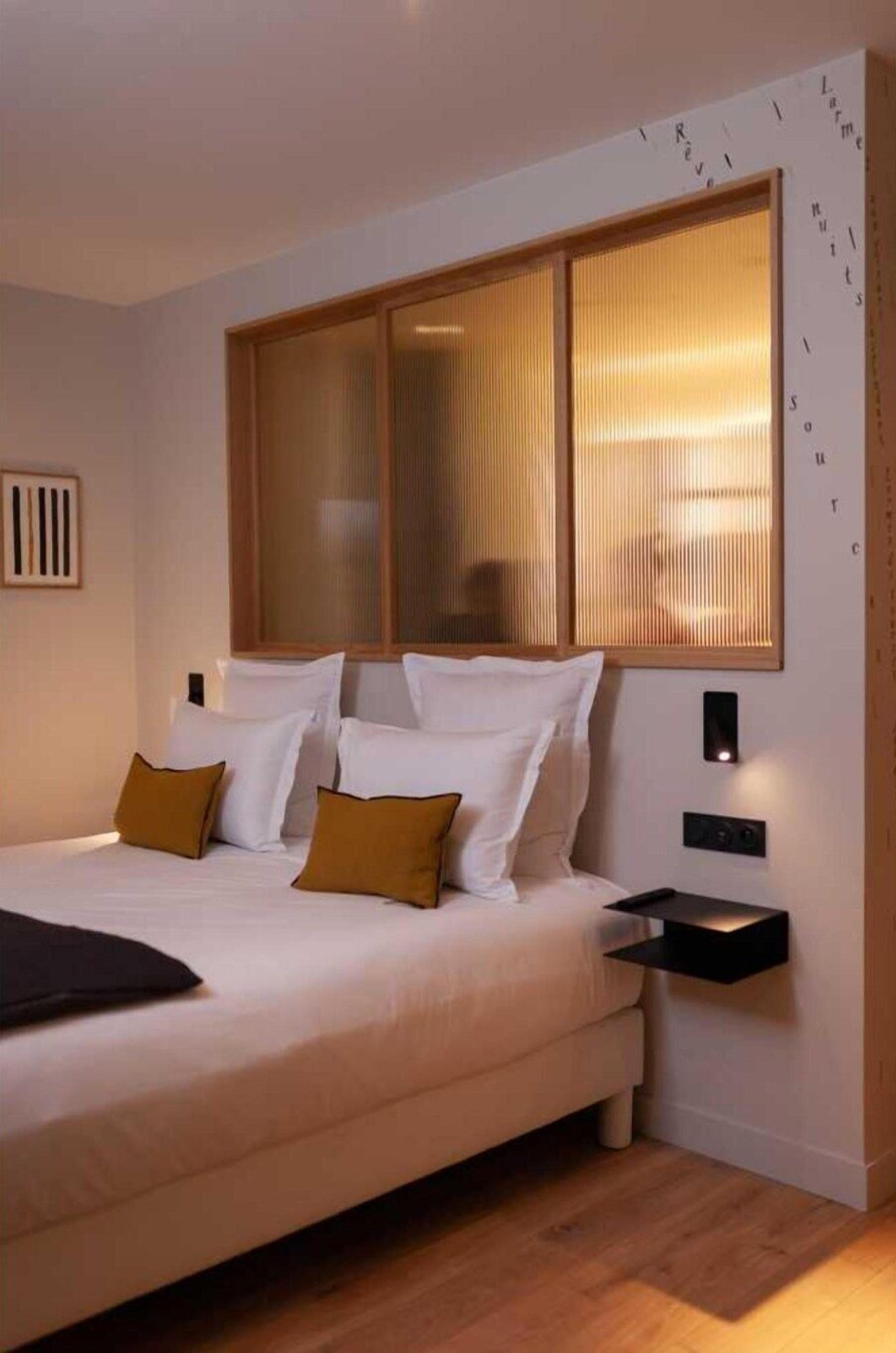 Ein modernes Schlafzimmer mit einem großen Bett, einem Holz-Kopfteil und einem Nachttisch mit Lampe.