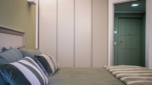 Een slaapkamer met een bed, kussens, een kast en een deur.