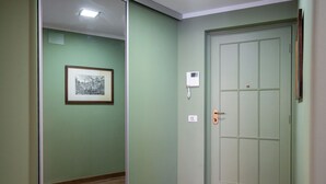 Een gang met een groene muur, een lijst met afbeelding, een deur met slot en een telefoon aan de muur.