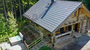 A log cabin with a metal roof, a hot tub, and a wooden deck.