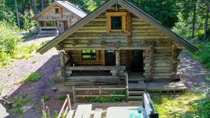 A log cabin with a porch and a hot tub.