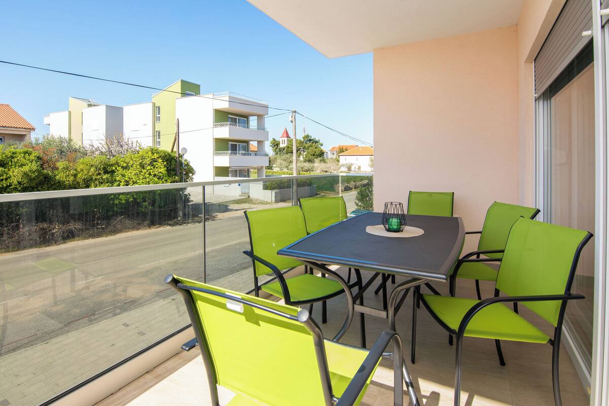 Ein Balkon mit Tisch und Stühlen, mit Blick auf eine Straße und Gebäude.