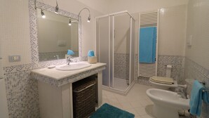 Ein Badezimmer mit Waschbecken, Spiegel, Dusche, Toilette und Bidet.