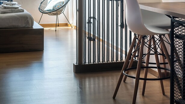 A modern living room with a wooden floor, a white sofa, a black and white striped partition, and a view of a building outside.