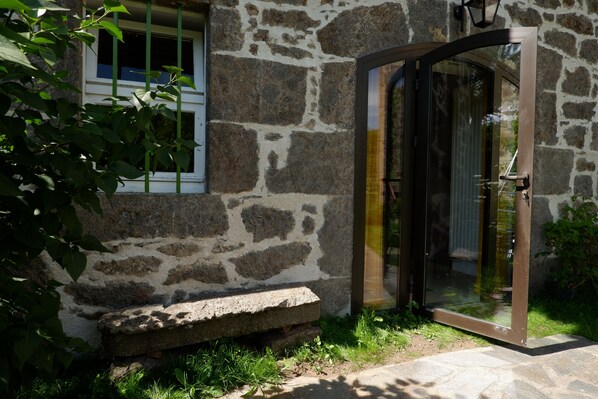 Un edificio in pietra con una porta in vetro e una piccola panchina di pietra all'esterno.