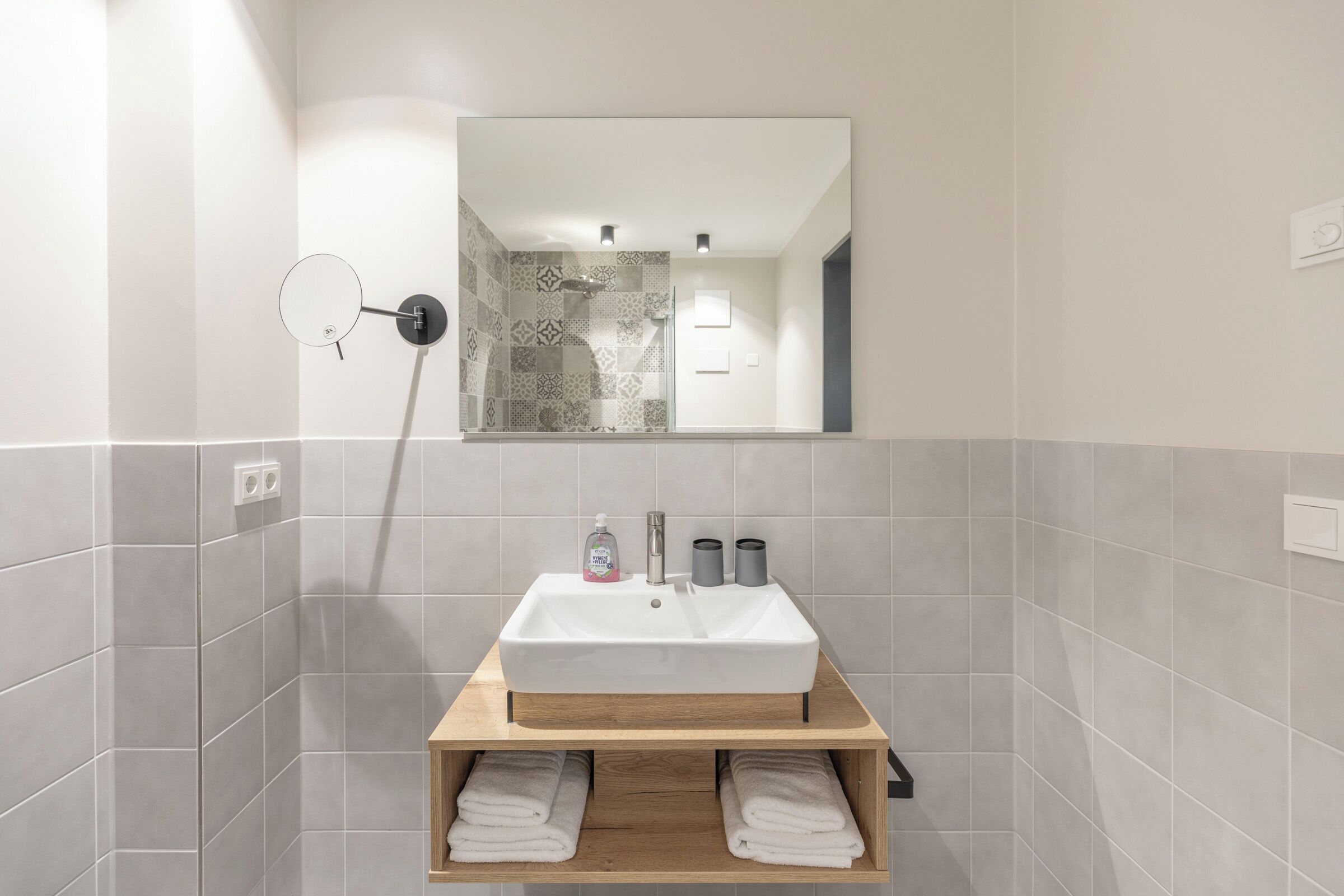 Une salle de bain avec un lavabo blanc, un meuble-lavabo en bois et un miroir au-dessus.
