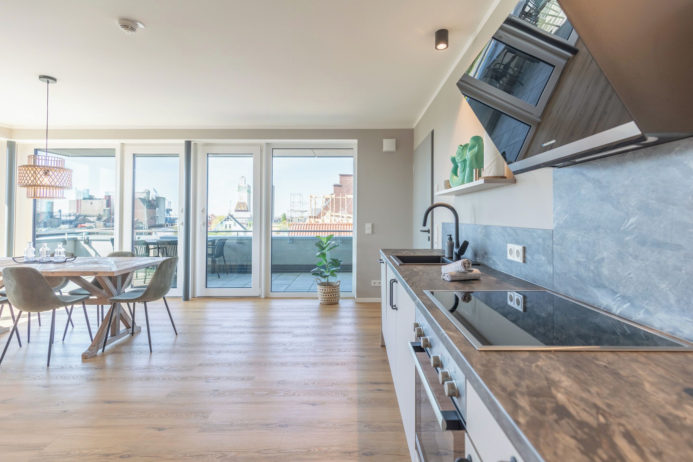 A modern kitchen with a wooden countertop, a built-in oven, and a large window overlooking an urban area.
