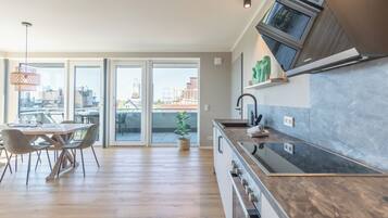 A modern kitchen with a wooden countertop, a built-in oven, and a large window overlooking an urban area.