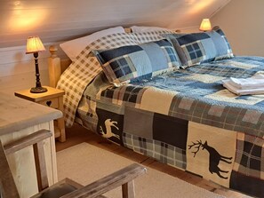 Cozy bedroom with a large bed, nightstands, and a wooden bench, set against a rustic backdrop.