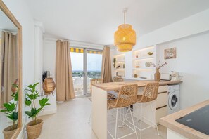 Een moderne keuken met een centraal eiland, barkrukken en een wasmachine.