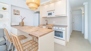 Une cuisine moderne avec un îlot central, des meubles blancs et un four à micro-ondes placé au-dessus de la cuisinière.