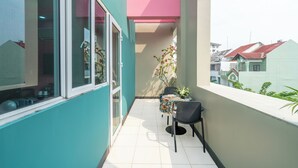 A balcony with a table and chairs, a potted plant, and a view of neighboring buildings. - La Bonita Hotel & Apartments (Ho Chi Minh City)