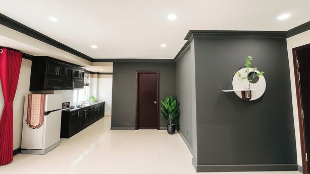 A modern kitchen with dark cabinetry, a refrigerator, and a potted plant. - La Bonita Hotel & Apartments (Ho Chi Minh City)