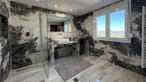 A modern bathroom with a glass shower enclosure, a large sink, and a window offering a view. - Heavens Balcony Meteora (Kalabaka)