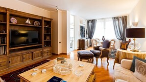 A living room with a wooden entertainment unit, a flat-screen TV, a coffee table with decorative items, and a sofa with cushions. - Casa Azul in Sorrento center - My Rental Homes (Sorrento)
