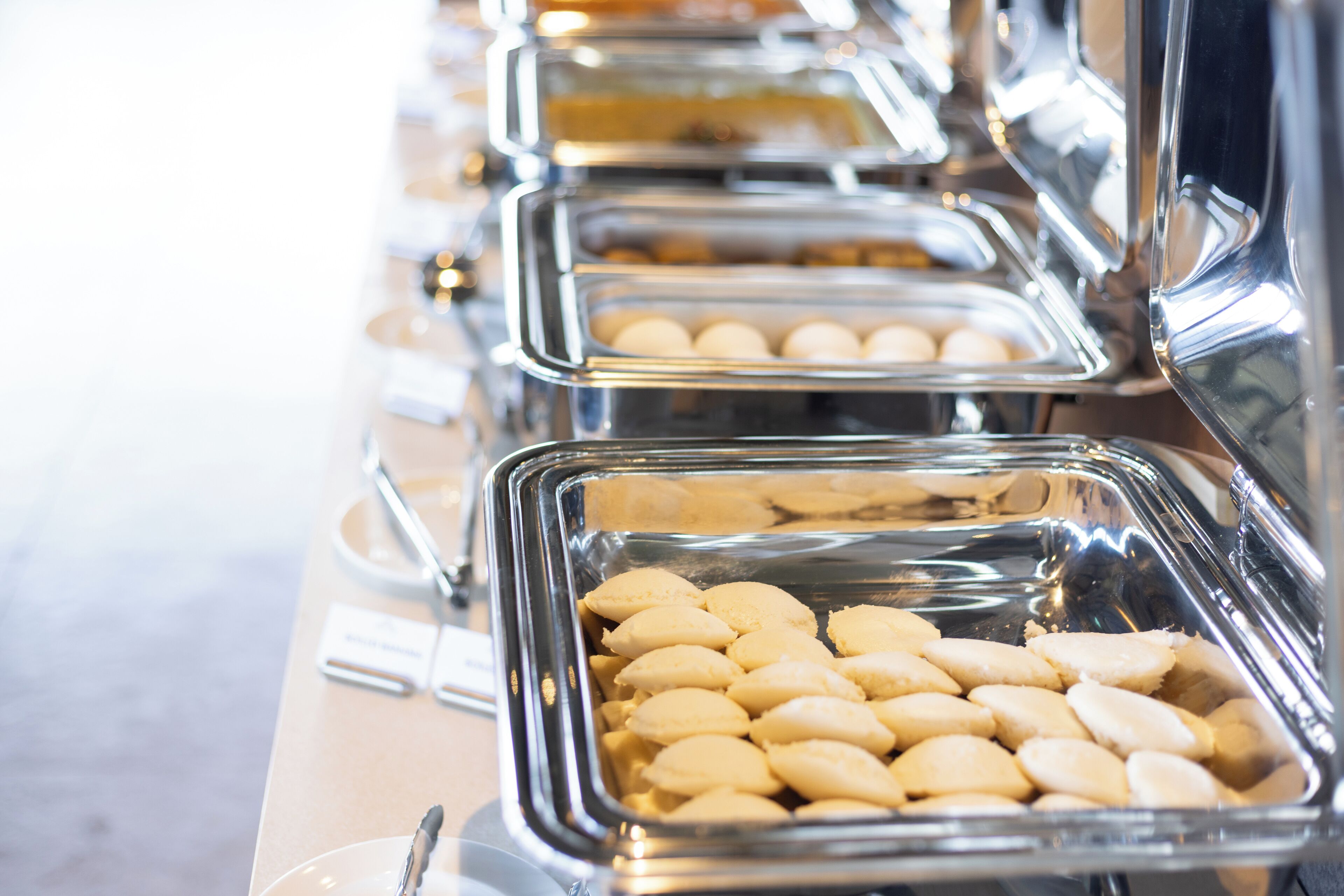 A buffet line with multiple serving trays containing various food items.
