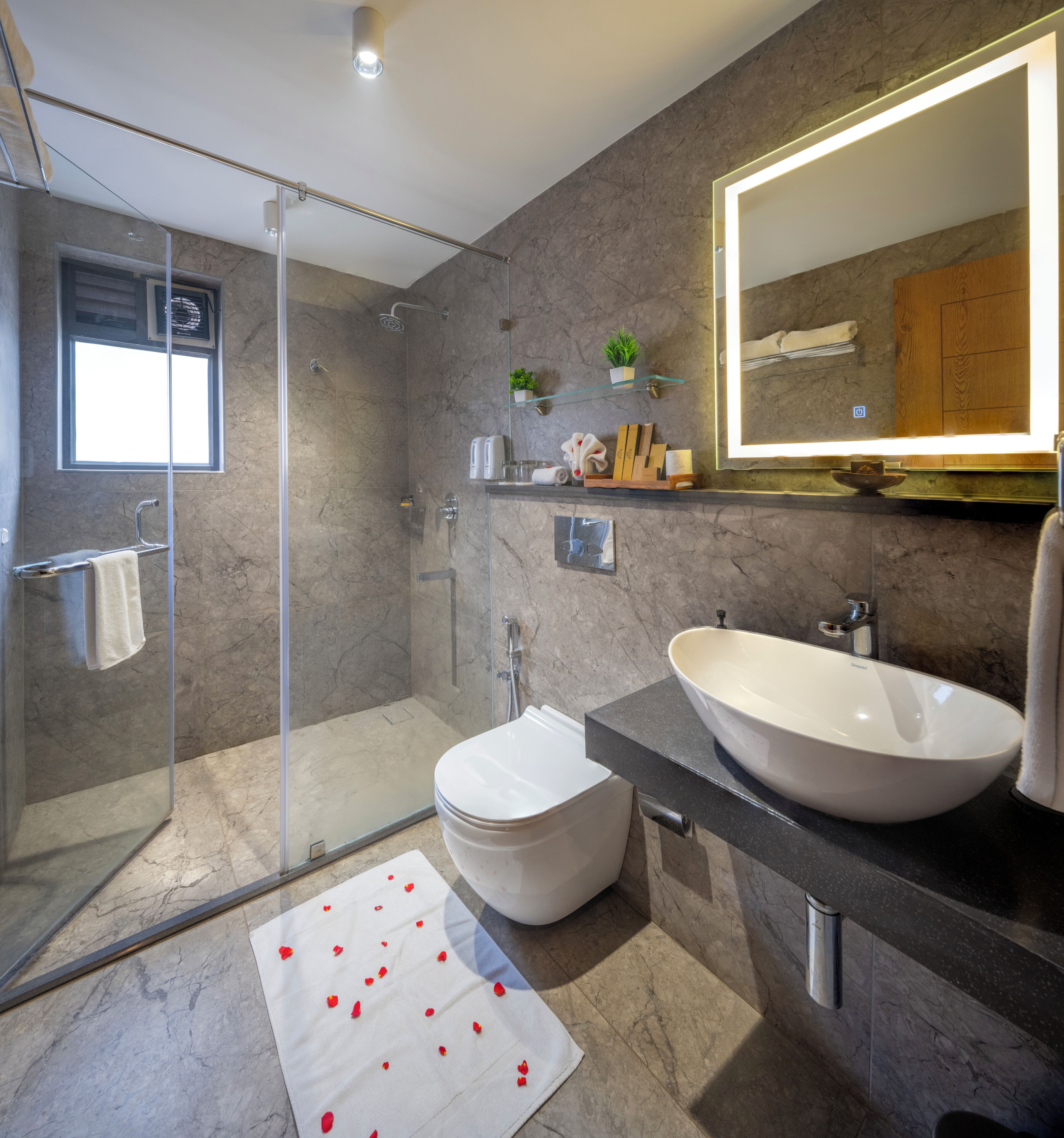 Un baño moderno con cabina de ducha de vidrio, un inodoro blanco, un lavamanos tipo cuenco grande y un espejo con marco de madera.