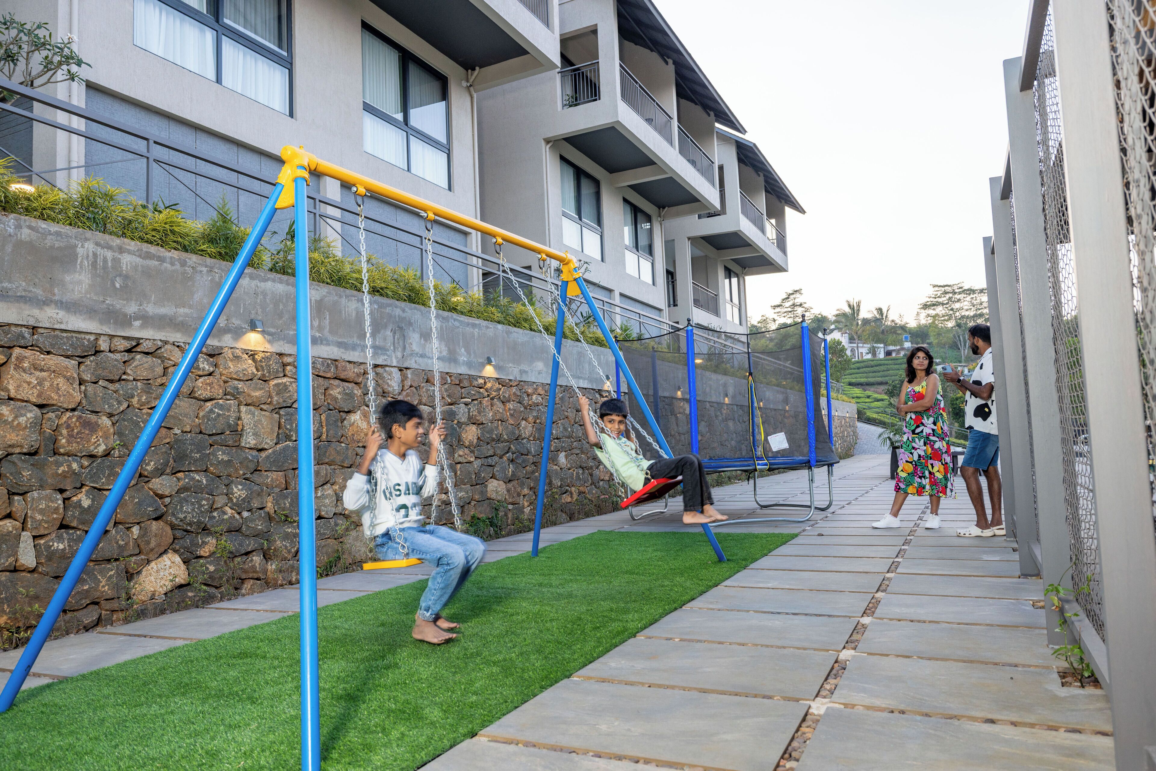 A residential area with a swing set and a stone wall.