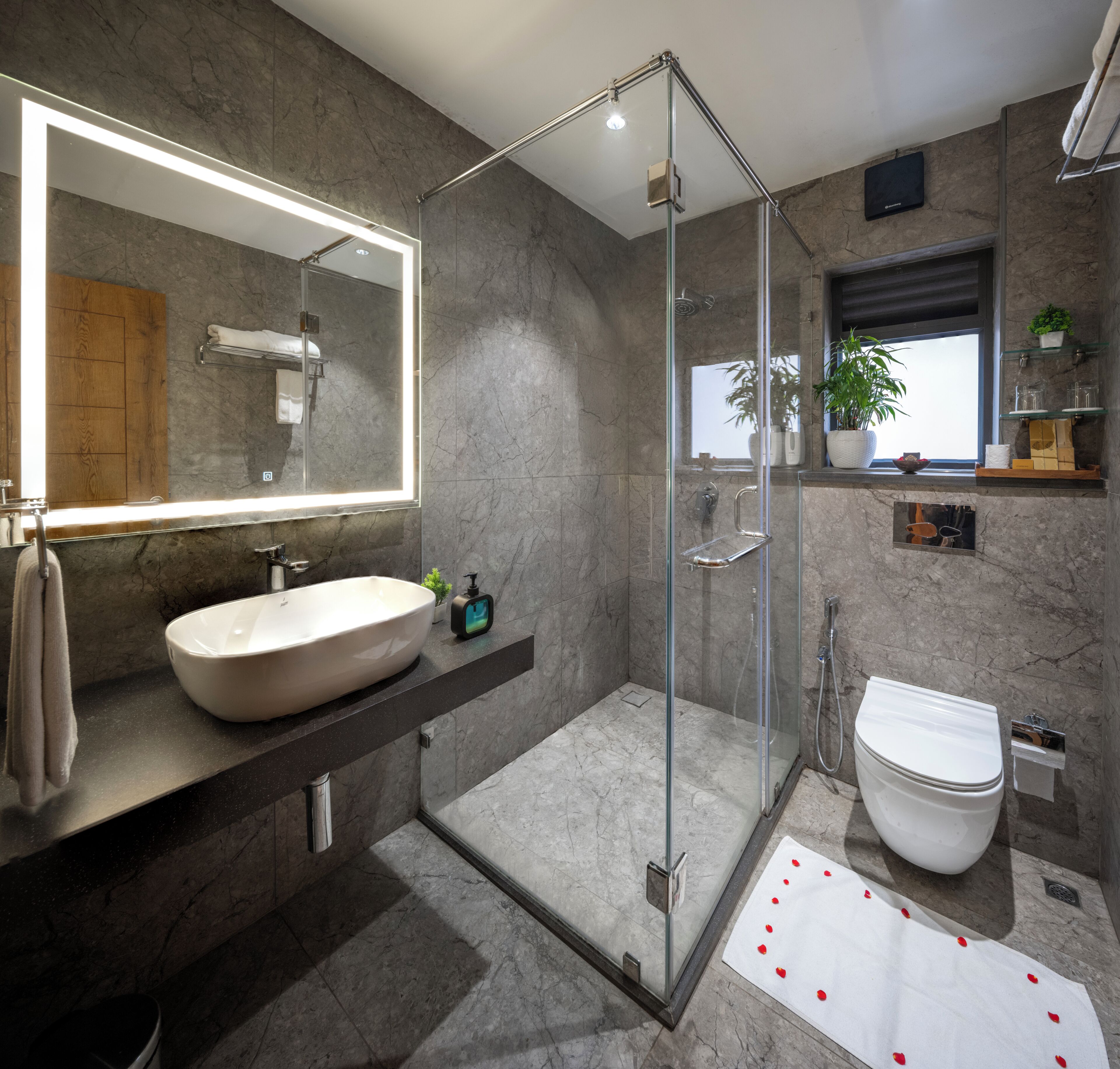 A modern bathroom with a large mirror, a vessel sink, a glass-enclosed shower, and a toilet.