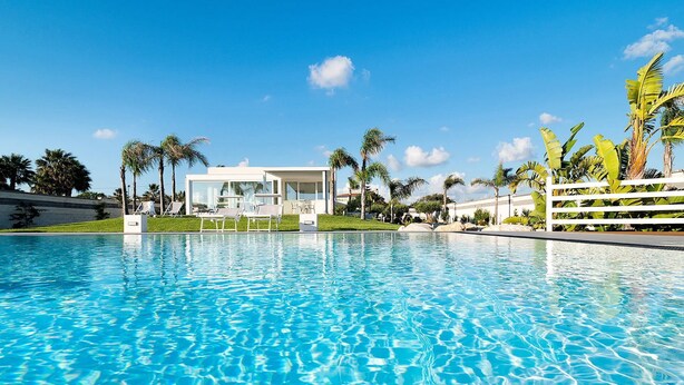 A clear blue pool with lounge chairs and palm trees. - Casa Sunnshine with shared pool - My Rental Homes (Marsala)