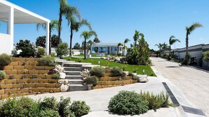 A modern house with a pool, surrounded by palm trees and a well-maintained garden. - Casa Sunnshine with shared pool - My Rental Homes (Marsala)