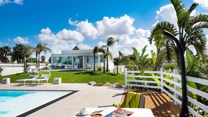 A modern house with a pool, lounge chairs, and a wooden deck with a white fence. - Casa Sunnshine with shared pool - My Rental Homes (Marsala)