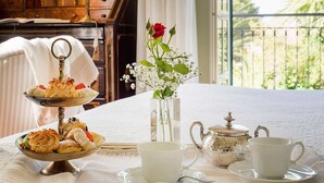 A breakfast setup with a tiered dessert stand, a vase with flowers, a teapot, and two cups on a table. - Green Villa with heated pool - My Rental Homes (Salemi)