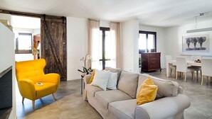 A modern living room with a sofa, a yellow armchair, and a dining area with a table and chairs.