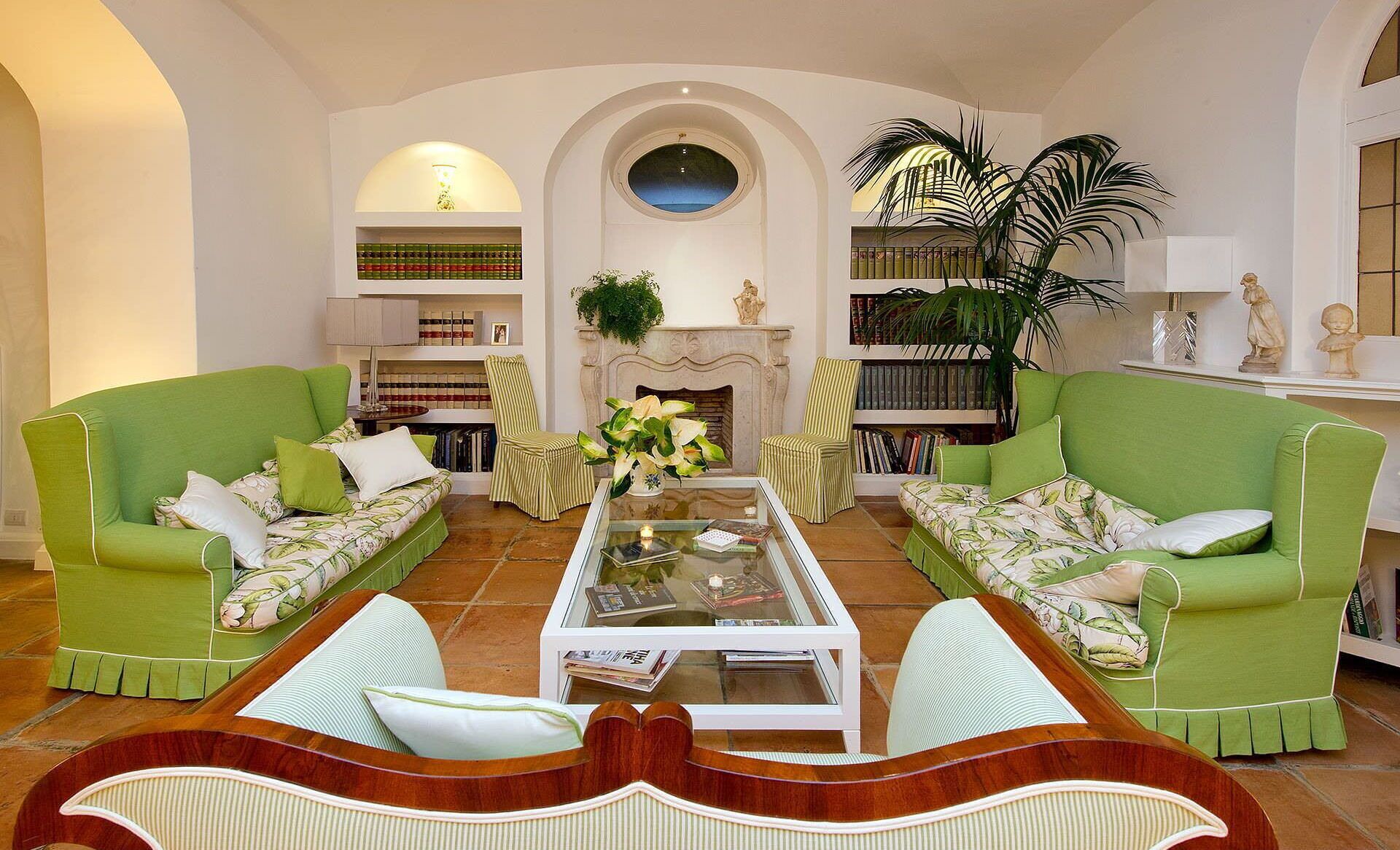 Ein Wohnzimmer mit zwei grünen Sofas, einem Couchtisch und einem Kamin.