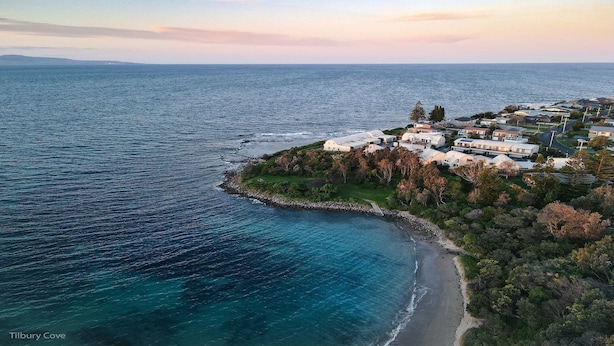 An aerial view of a coastal residential area with houses along the shoreline, a beach, and a cove. - 2 Storey family home just steps away from the beach! (Culburra Beach)
