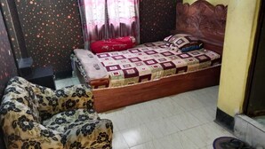 A bedroom with a bed, a sofa, a window with curtains, and a tiled floor. - Hotel New Royal Jatrabari (Dhaka)