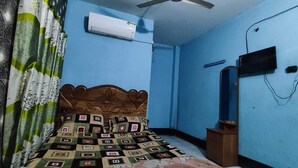A bedroom with a bed, an air conditioner, a wooden headboard, a mirror, and a television. - Hotel New Royal Jatrabari (Dhaka)