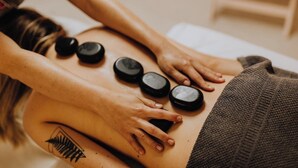 A person receiving a back massage with multiple stones placed on their back. - Hotel New Royal Jatrabari (Dhaka)
