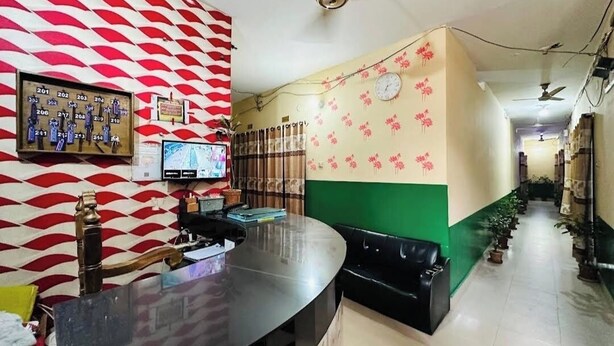 A reception area with a counter, a television, and a patterned wall. - Hotel New Royal Jatrabari (Dhaka)