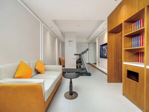 Una sala de estar moderna con un sofá, una cinta de correr y una estantería.